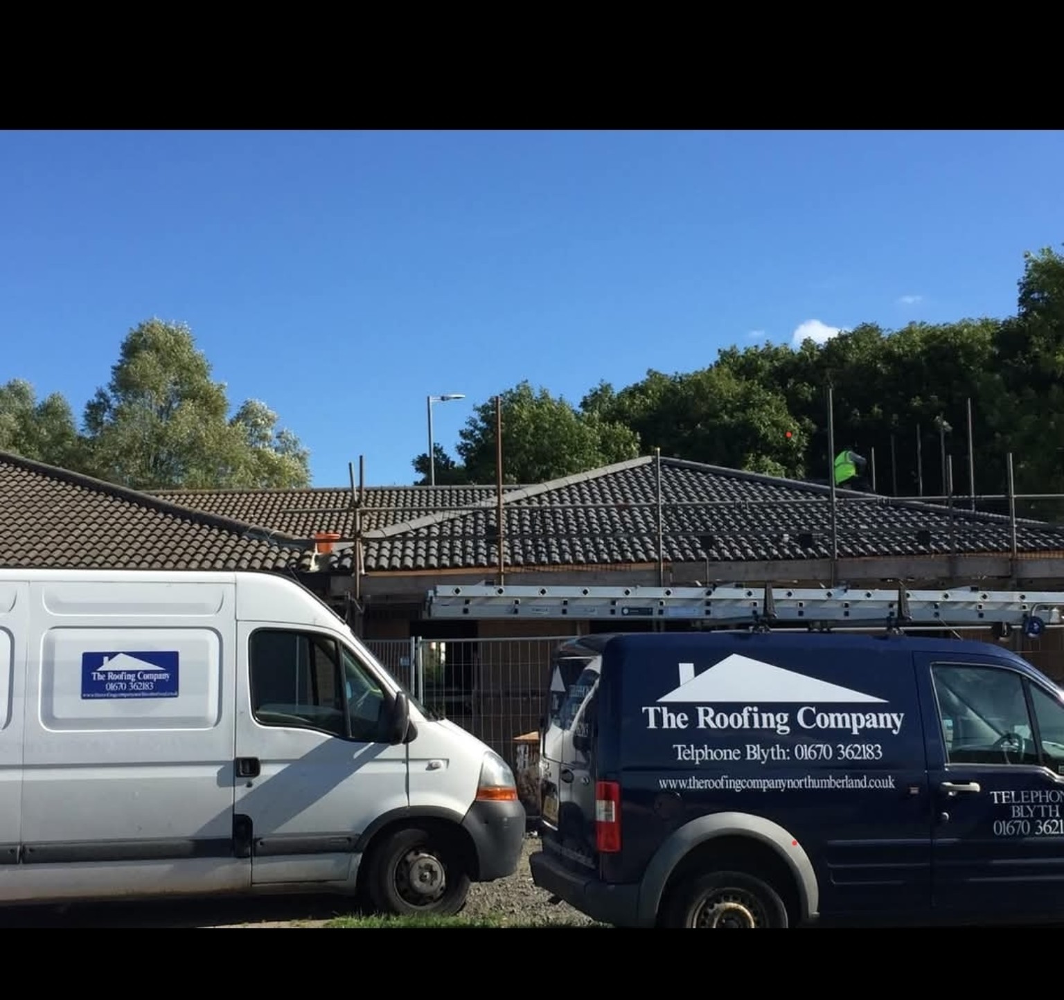 The Roofing Company branded work vehicles on site